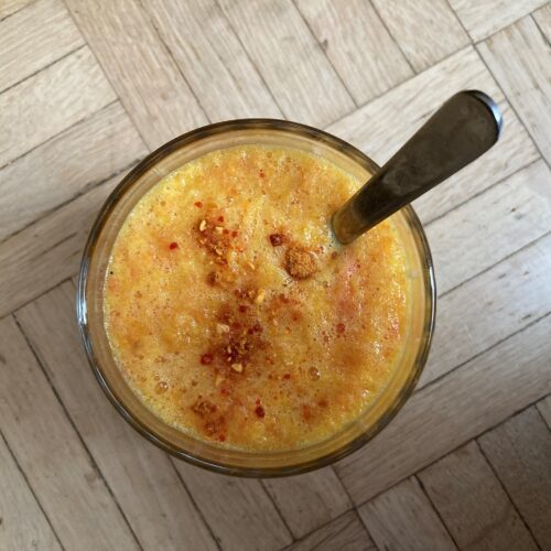 Turmeric-ginger shot in a glass dusted with rosehip powder
